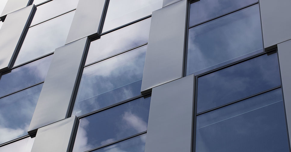 Uma fachada de ACM de cor cinza e com vidro